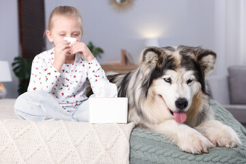 Girl suffering from allergy with her dog on bed at home