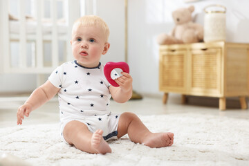 Cute baby playing with toy on carpet in light room