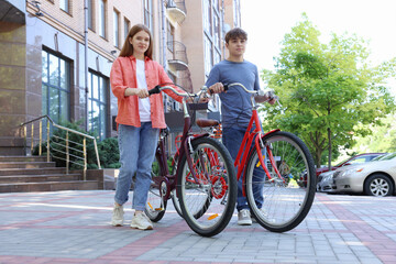 Teenage girl and boy with bicycles on city street