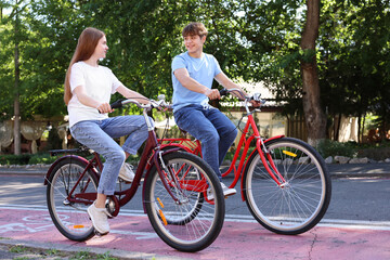 Teenage girl and boy riding bicycles on city street