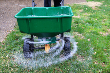  A seed and fertilizer spreader sitting out on a lawn