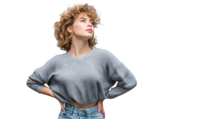 Young woman with curly blonde hair in a grey sweater and jeans looking up against black background
