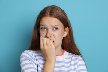 Teenage girl suffering from panic attack on light blue background