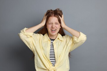 Teenage girl suffering from panic attack on grey background