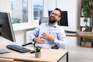Man in glasses laughing at table in office