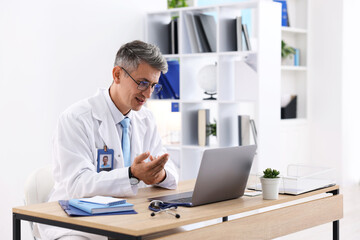 Fototapeta premium Telemedicine. Doctor having video call with patient via laptop indoors