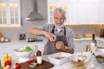 Smiling elderly man cooking at table in kitchen