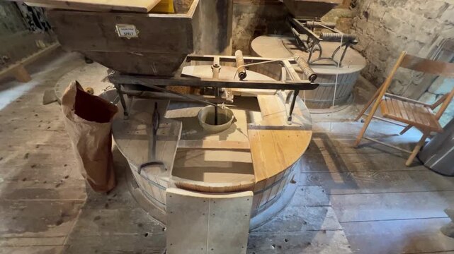Millstone in action stone grinding grain spelt in an old mill for flour production