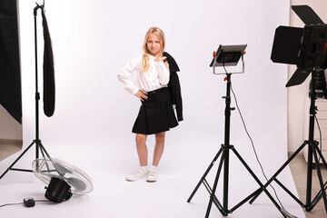Little girl on white background in photo studio with professional equipment