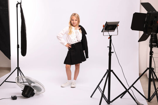 Little girl on white background in photo studio with professional equipment