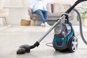 Man resting on sofa at home, focus on vacuum cleaner