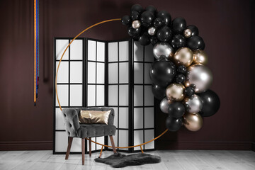 Stylish photo zone with balloons, armchair and decor in studio