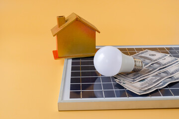 Composition with solar panel, led lamp, money and model house on texture background.