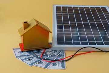 Composition with solar panel and model house on background.