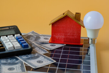 Composition with solar panel, led lamp, money and model house on texture background.
