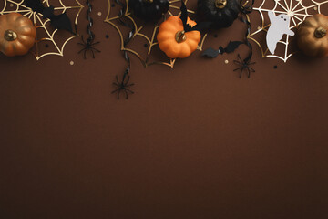 Halloween background in dark brown color with party decorations from pumpkins, bats, spiderweb top...