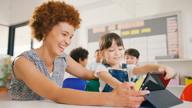 Teacher With Female Elementary School Student Using Digital Tablet In STEM Class