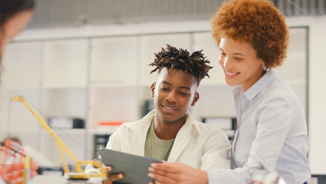 Female Teacher With Male High School Student Using Digital Tablet In STEM Class