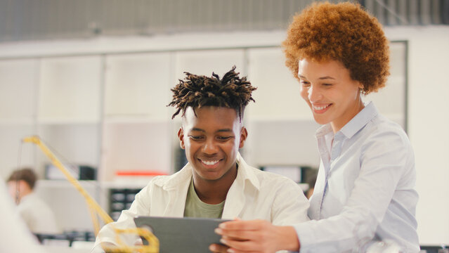 Female Teacher With Male High School Student Using Digital Tablet In STEM Class