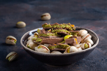 Dubai chocolate bar with filling made of kataifi (knafeh, kadayif) and pistachio  paste. Trendy chocolate on dark background.