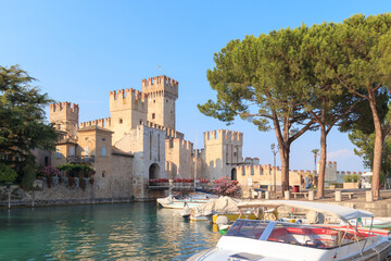 Sirmione at Lake Garda features a historic castle surrounded by clear waters. Clear blue sky day and picturesque scenery of Italy. © 24K-Production