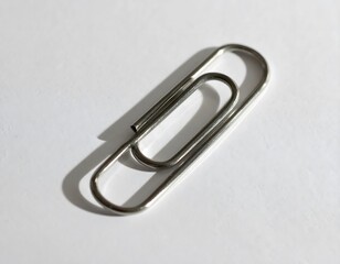 Classic metal paperclip isolated on a clean white surface with a soft shadow. Essential office and school stationery for organizing documents.