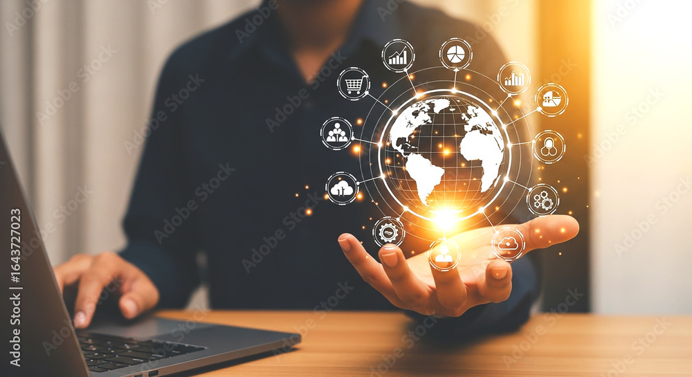 Poster person using laptop with glowing digital globe and icons floating above their hand showing global te