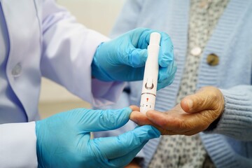 Asian doctor using digital glucose meter for check sample blood sugar level to treatment diabetes.