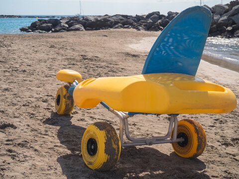Fototapeta A beach wheelchair parked on the sand provides access for individuals with mobility challenges. The gentle waves and clear sky enhance the inviting atmosphere of the beach.