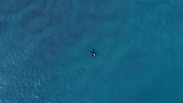 Person Floating Alone in Vast Blue Ocean Seen From Above