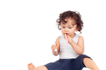 Curly haired toddler brushing teeth with toothbrush and holding toothpaste