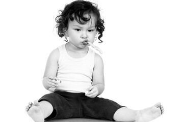 Curly haired toddler brushing teeth with toothbrush and holding toothpaste