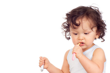 Curly haired toddler brushing teeth with toothbrush and holding toothpaste