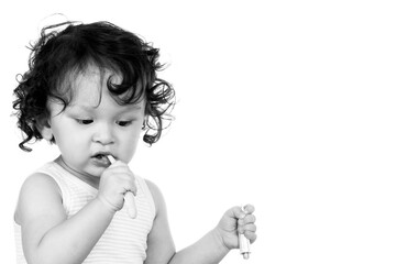 Curly haired toddler brushing teeth with toothbrush and holding toothpaste