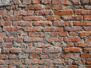 The texture of a very old vintage brick wall with residual elements of plaster decoration.