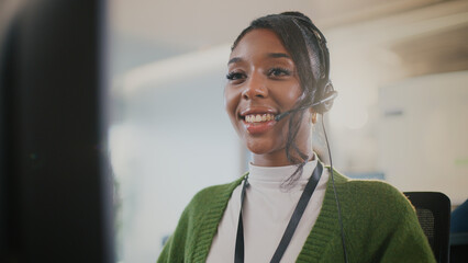 Confident African American female call center employee in headset offering customer support, tech...