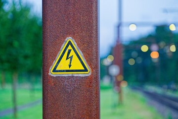 Rusty metal beam with yellow electric warning triangle sign