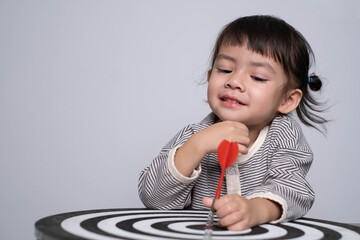 A cheerful child plays with a dart on a bullseye board, showcasing focus and joy in a playful setting.