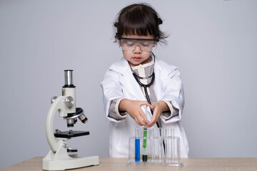 A young child in a lab coat uses a microscope and test tubes, showcasing early interest in science and experimentation.