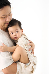 Close-up of Asian toddler boy wrapped in a blanket, sitting in father's arms, father looking down at child affectionately