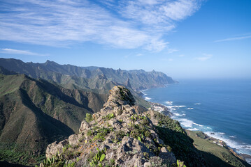 Stunning coastal view from a mountain peak with rugged cliffs and rolling waves along the coastline during clear weather