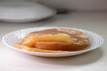 A gently glistening kombucha SCOBY rests on a decorative plate, showcasing its smooth texture and rich color. This fermentation culture is central to brewing kombucha in a contemporary kitchen.