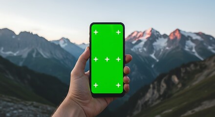 Hand holding phone with green screen in front of a beautiful mountain landscape