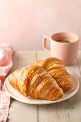 Plate of two freshly baked croissants and cup of black coffee