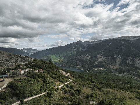 Aerial view of the ancient village clinging to the hillside, a tapestry of stone and green overlooking the tranquil lake and distant mountains, Frattura Vecchia, Scanno, Abruzzo, Italy.