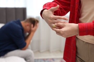 Woman taking off engagement ring after her husband's betrayal indoors, selective focus