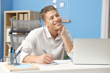 Naklejka premium Dream come true. Positive young man thinking about something at desk indoors