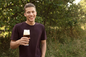 Young man with glass of beer outdoors