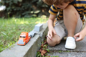 Little boy playing with toy car outdoors, closeup