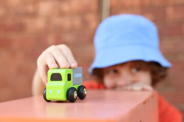 Little boy playing with toy car outdoors, selective focus